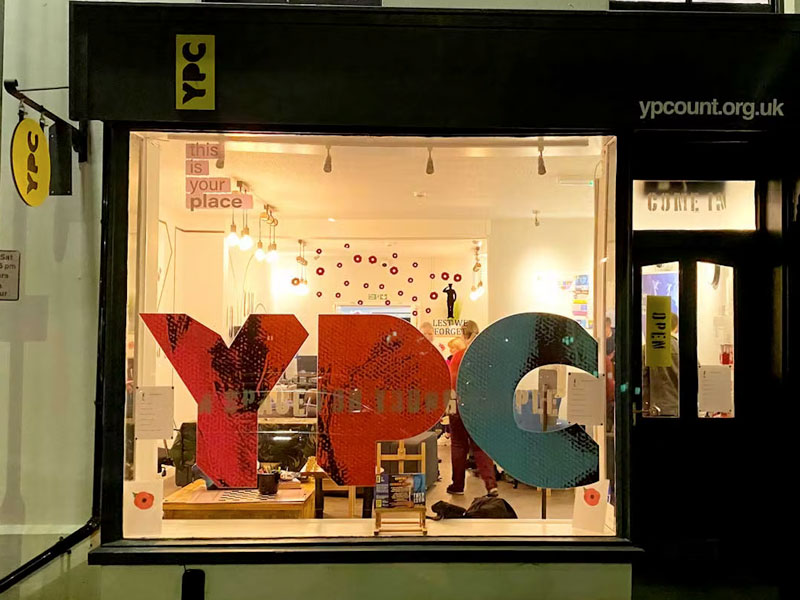 YPC Fascia Signage at night featuring vinyl window stickers, box sign, and swing sign